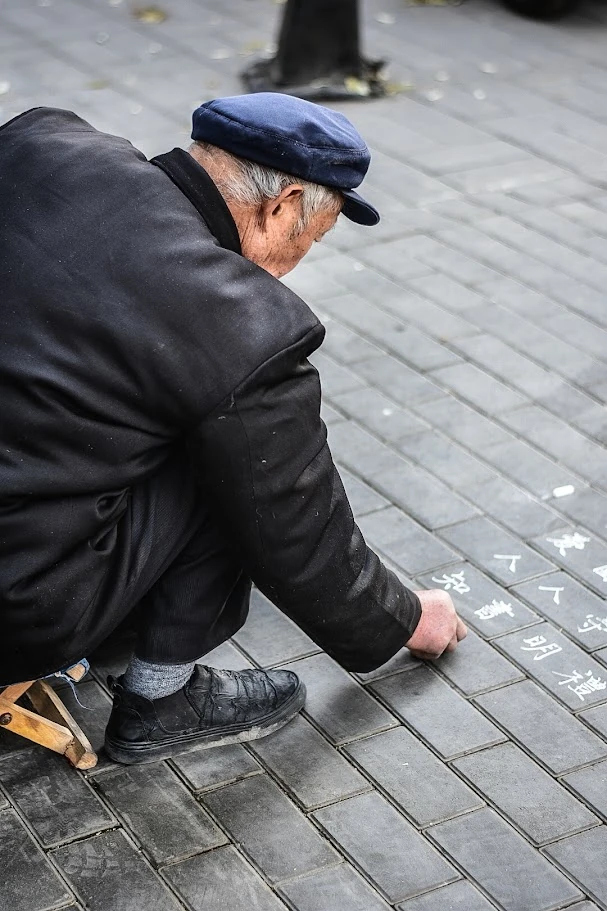 Old man writing on the street in Beijing, China